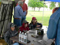 Huddling against the wind at the fly tying booth at the Outdoor Adventure Event